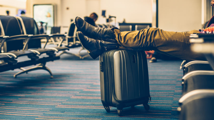 Passenger using carry on luggage as foot rest