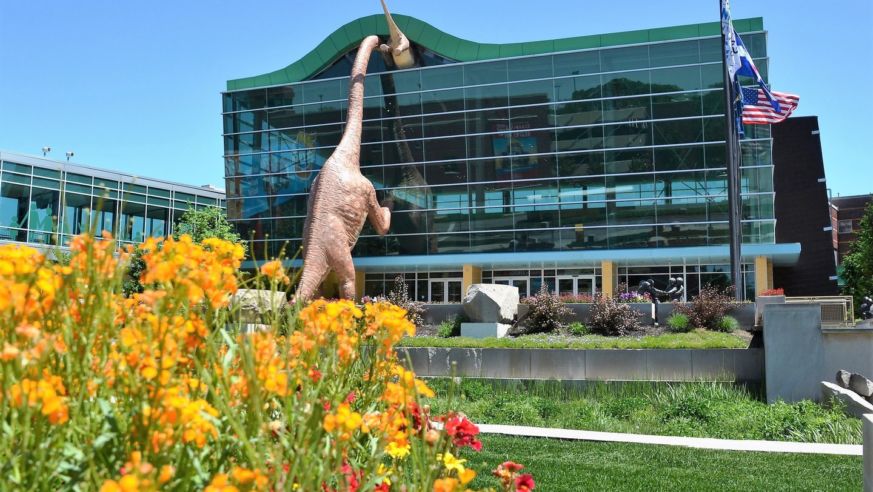 Dinosaur statues climbing into bulding