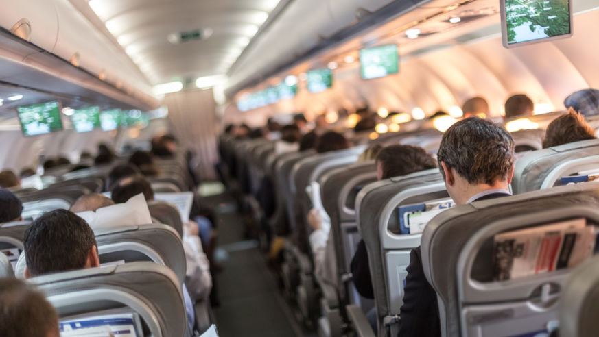 View from the back of a plane of crowded seats.