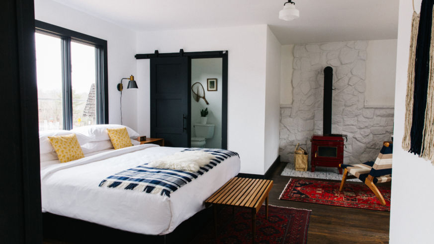 white and black room with queen bed and wood burning stove