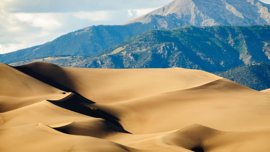 sand dunes with mountain range in backgroud