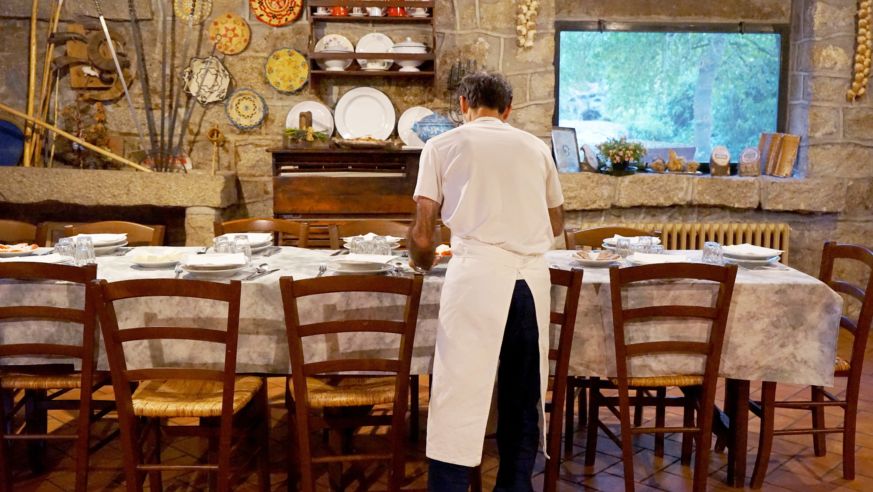 A view of an aproned waiter setting a table in Italy