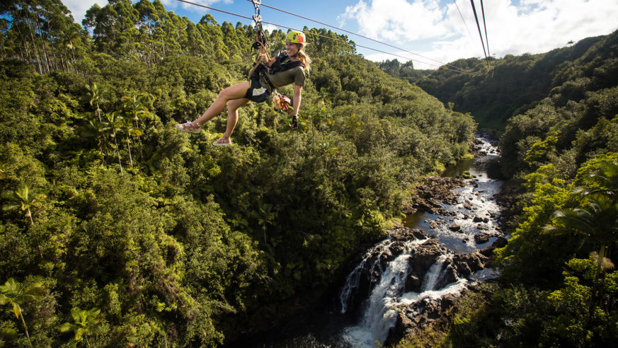 Woman on zipline over river and waterfall