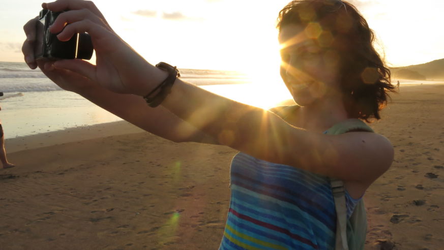 A solo traveler takes a photo of herself on the beach in Playa Grande, Costa Rica