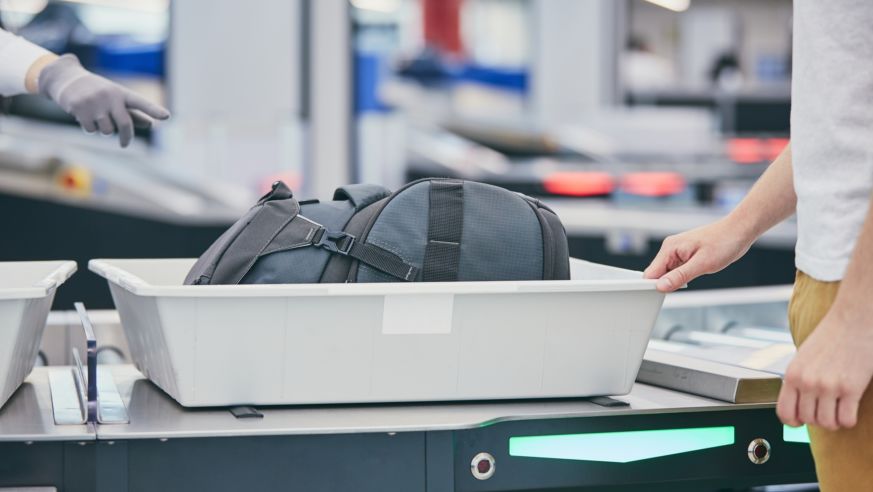 An airport security bin holds a passenger's bag awaiting x-ray