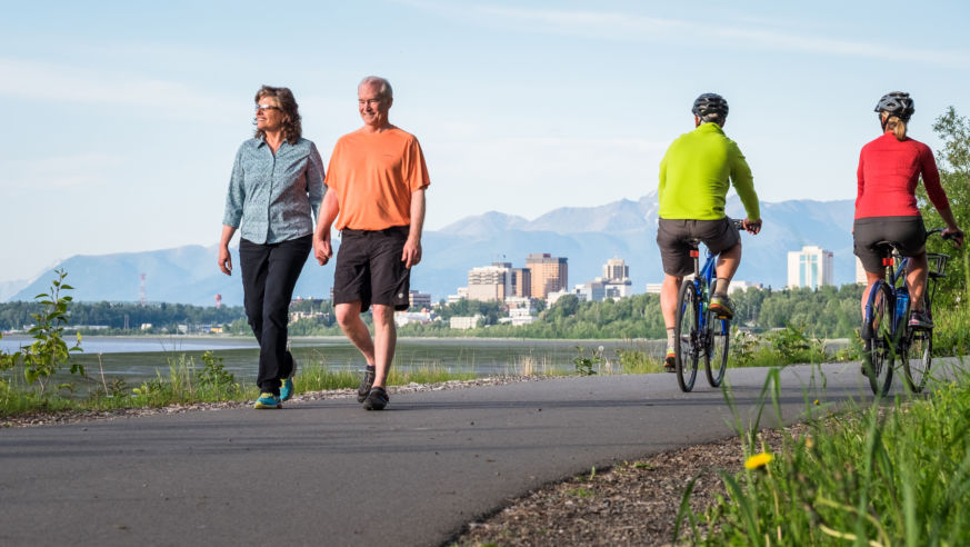 A view of Anchorage's coastal trail with couples walking and cycling
