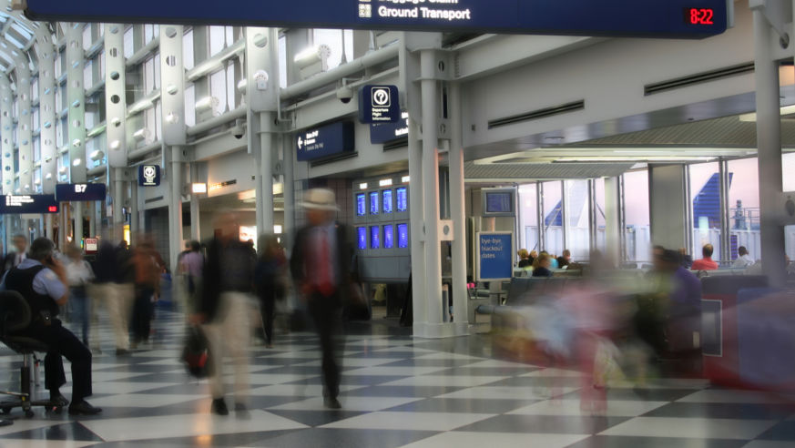 A view of a busy airport terminal with passengers moving quickly.