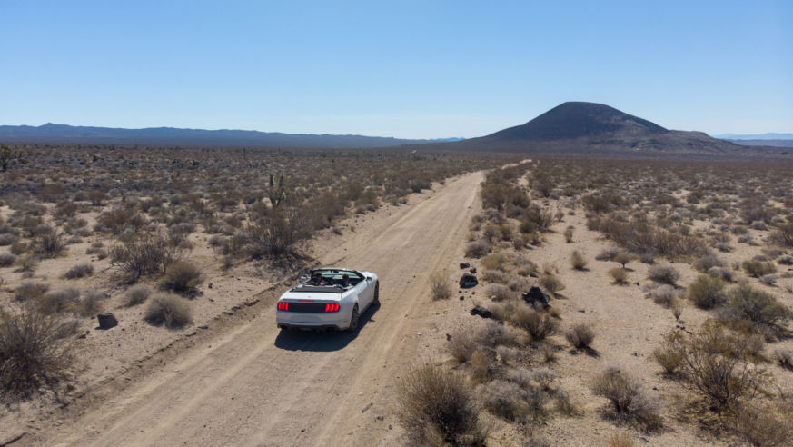 An overhead view of a car on a desert highway.