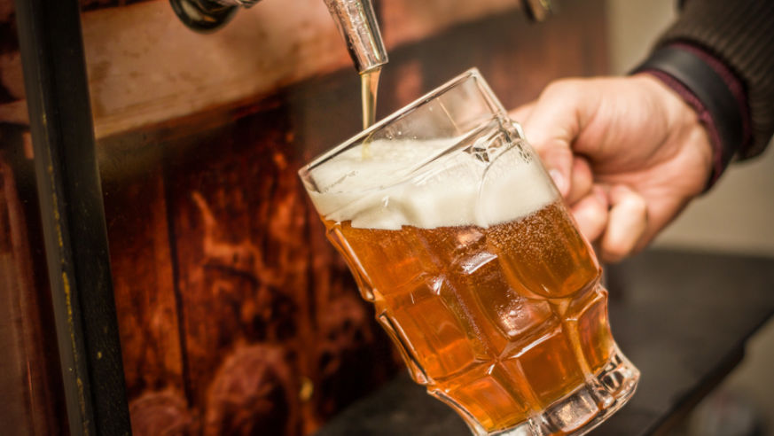A pint glass being filled with craft beer.