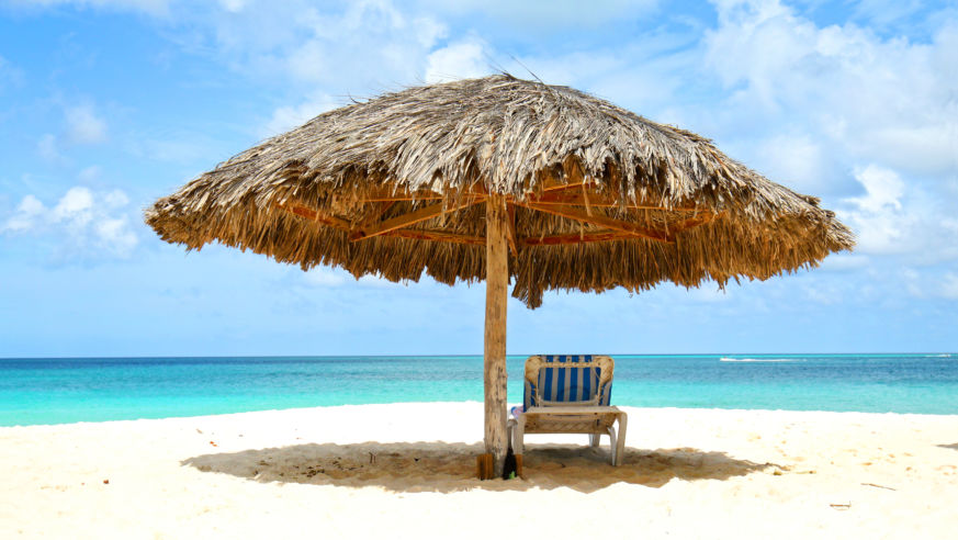A lounge chair under a grass umbrella