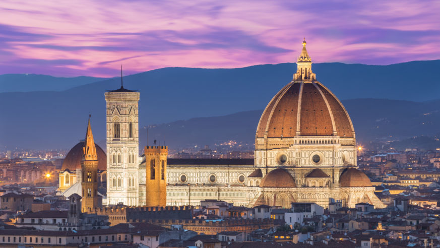 A panoramic view of Florence, Italy, with the Duomo and mountains in the background.