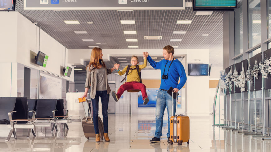 Mother and father lift toddler in the air at airport