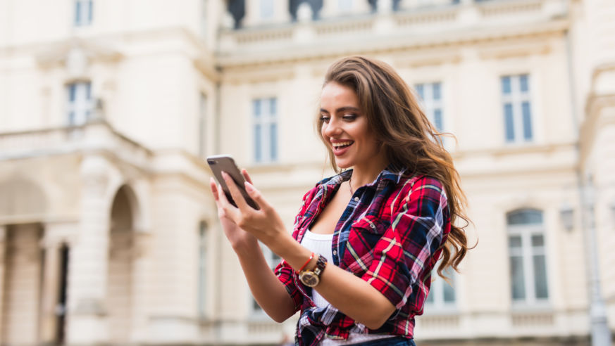 A smiling woman using her smartphone.