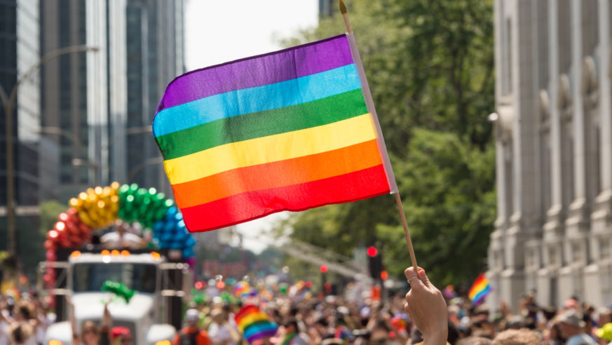 A view of Montreal's pride parade with a rainbow flag held high.