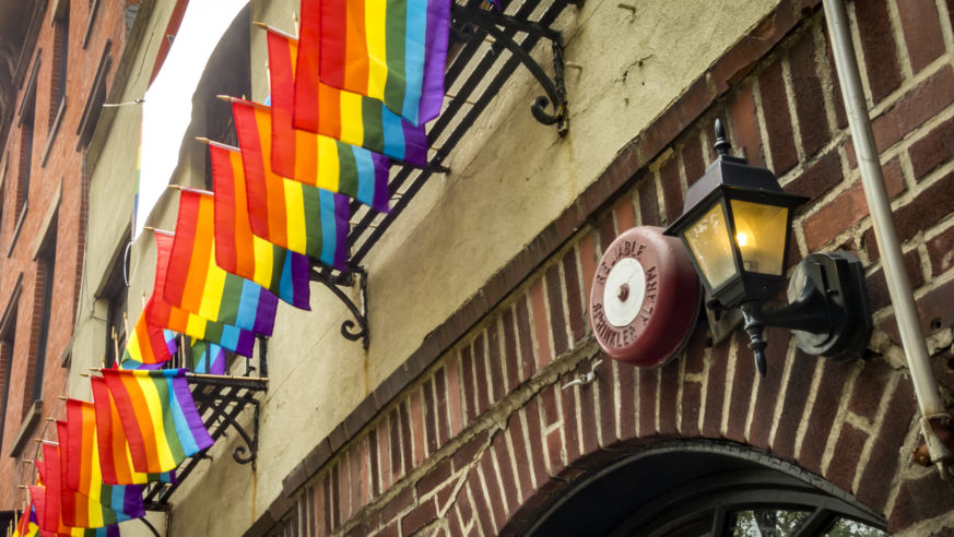 A street view of NYC's Stonewall Inn with rainbow flags.