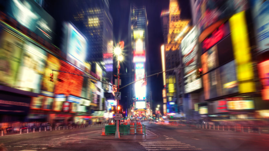 An action shot of people and traffic in NYC's Times Square.
