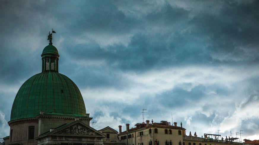 A dome in Venice with storm clouds gathering behind it.