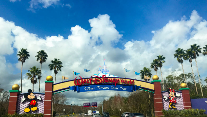 A view of cars entering Walt Disney World, Orlando, with a sign and image of Mickey Mouse
