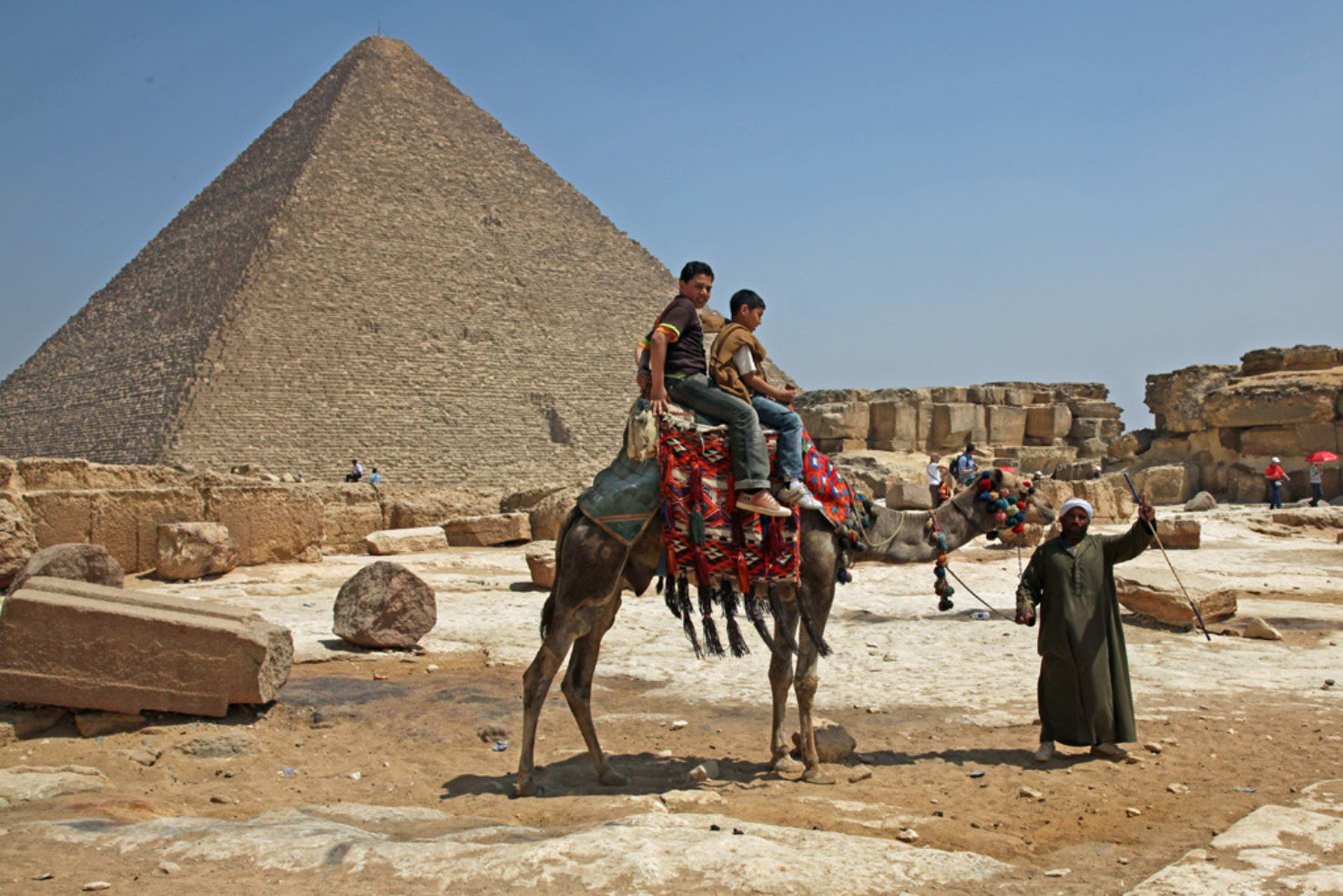 Children ride a camel in front of the Pyramids in Egypt