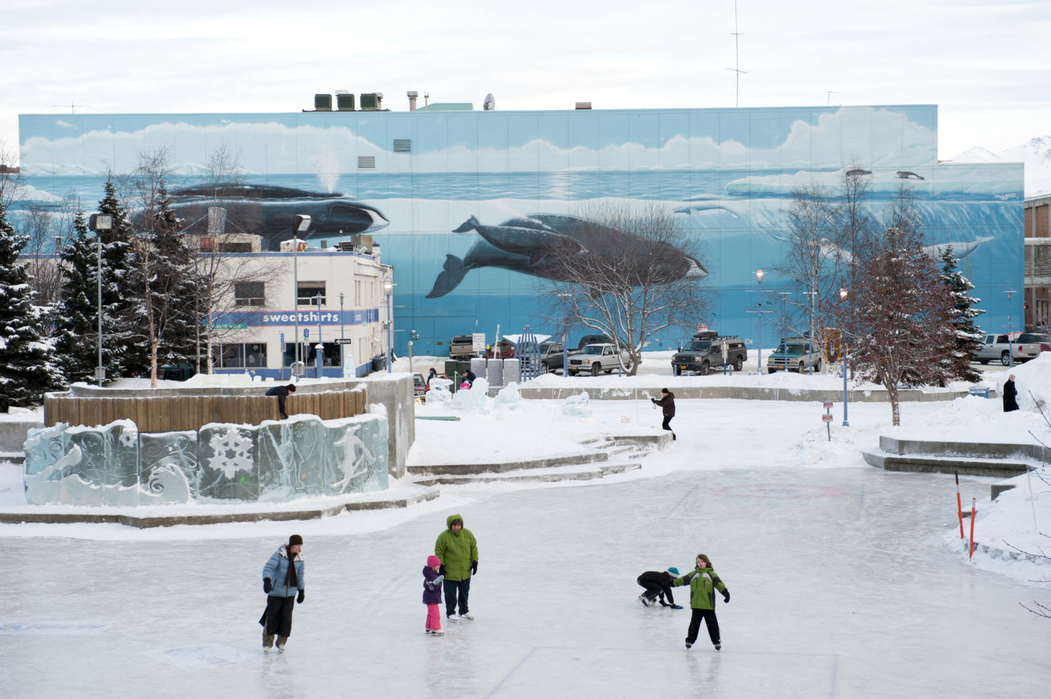 A family playing on an outside skating rink in downtown Anchorage, Alaska