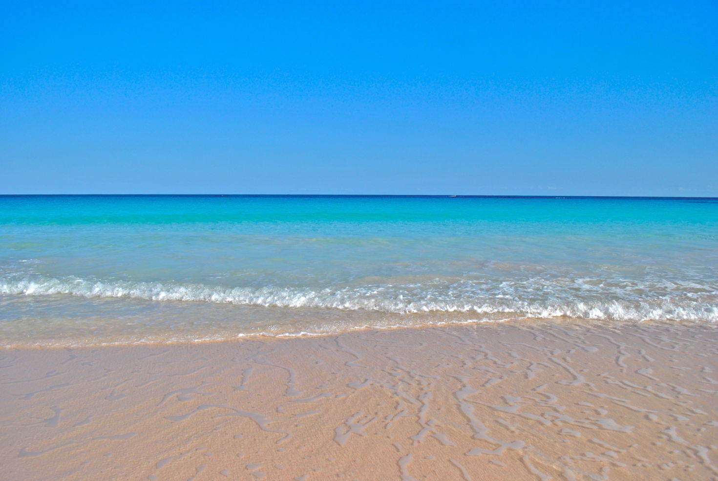 Gentle ocean waves lap the shore of Pink Sand Beach in Harbour Island, Bahamas.