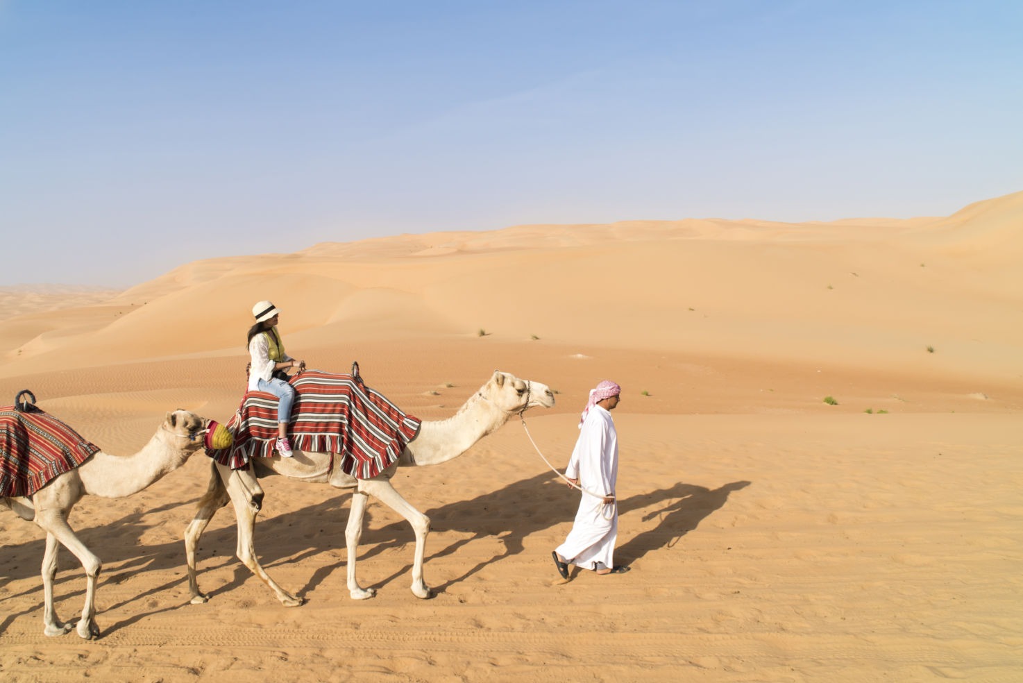 Woman on guided camel in desert of Abu Dhabi, U.A.E.