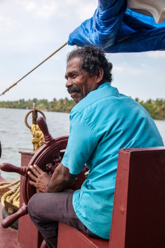 a man in blue steering kerala houseboat