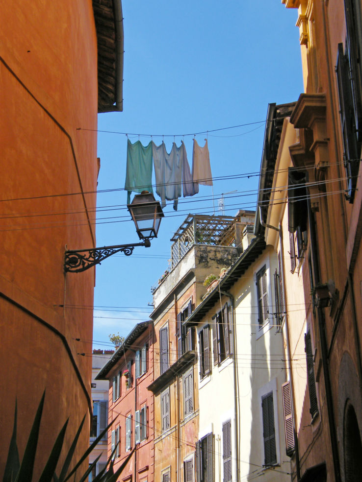 Laundry hanging high above the pedestrians on a line strung across the street on a glorious spring day in Rome.