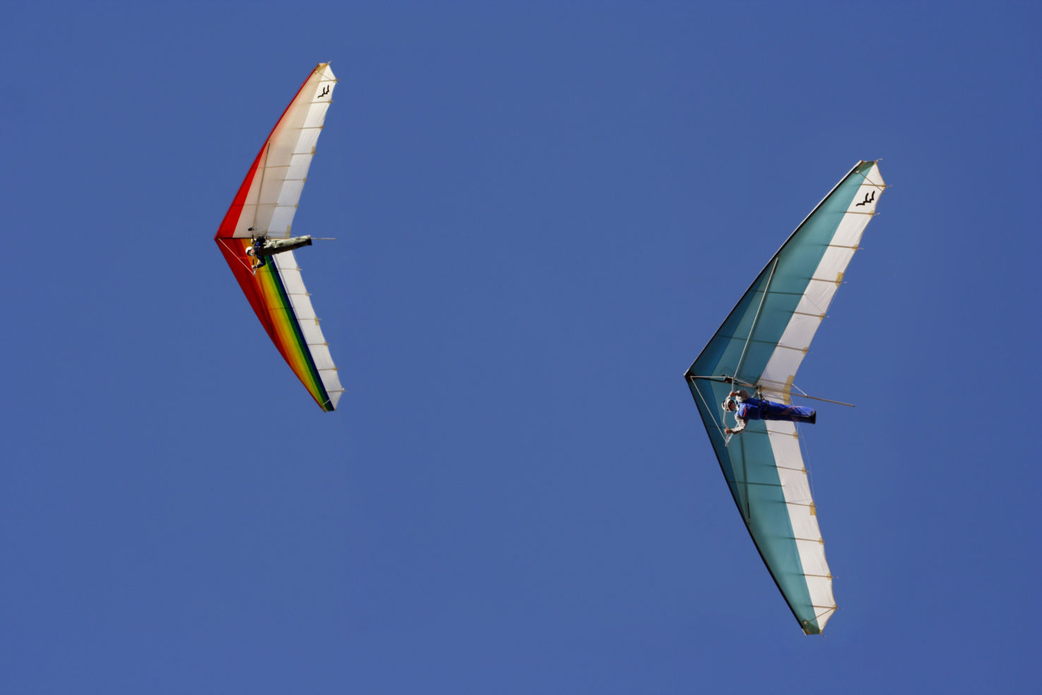 Hang gliders against blue sky.