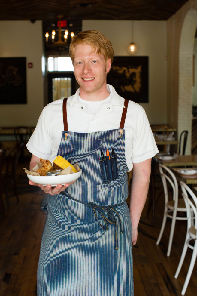 Sous chef Reid Shipman holds the restaurant’s signature pickled brine fried chicken with pepper gravy.